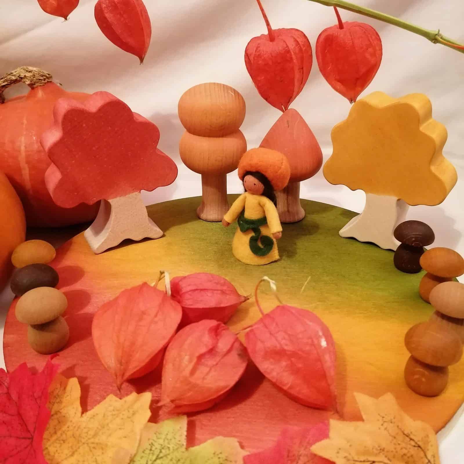 Small world homemade nature table display with woodstained board and trees with Ambrosious Pumkin fairy and natural loose parts