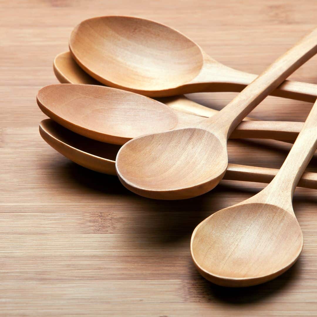 A stack of wooden spoons on a wooden table.