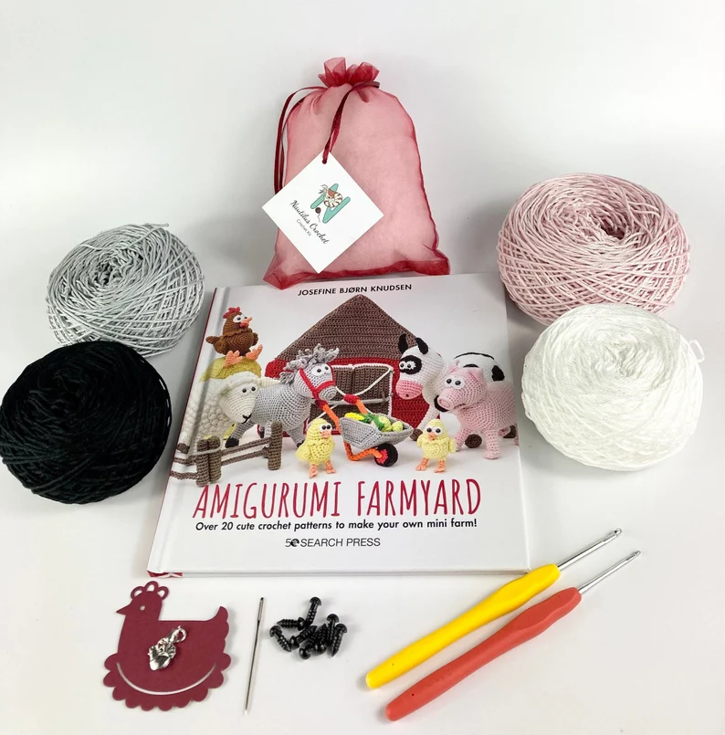 Crochet amigurumi farmyard kit with yarn, crochet hooks, a book and stuffing.