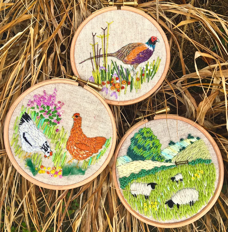 Three embroidery hoops with pheasant, hens and sheep