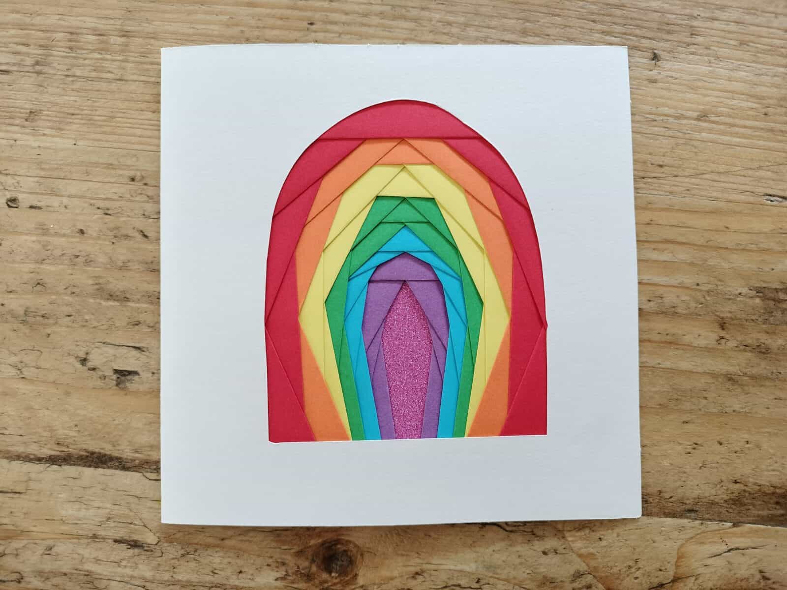 Iris folding card - vaulted archway using rainbow colours that start at red on the outside, then orange, yellow, green, blue, purple and pink sparkly card.