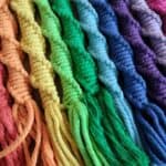Vibrant rainbow coloured yarn skeins arranged in a row, perfect for colourful crafting projects.