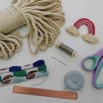 Colourful crafting supplies including yarn, scissors, thread, and tape on a white background, perfect for children's arts and crafts activities.